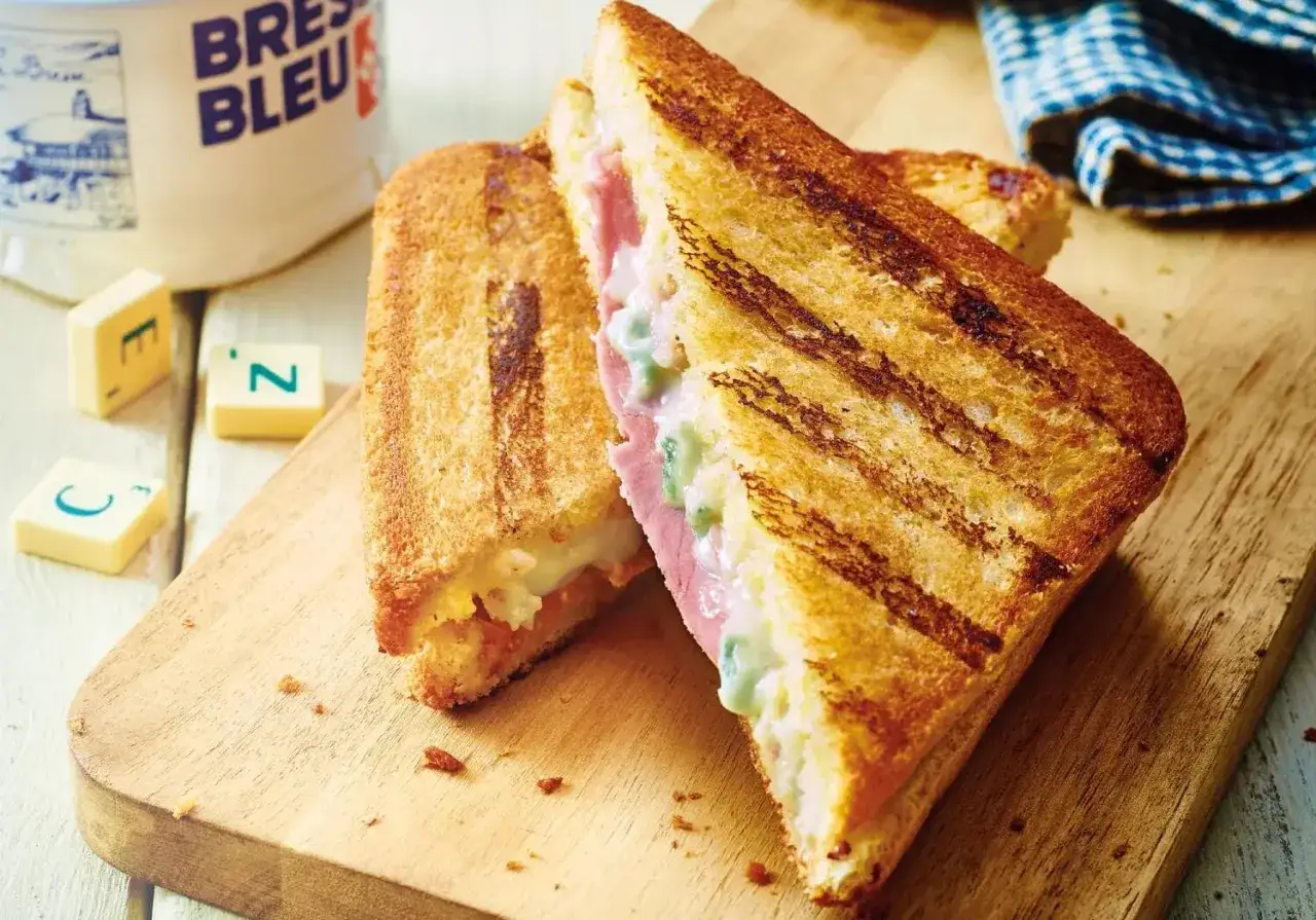Un délicieux fromage croque monsieur grillé, garni de jambon et de fromage fondant, sur une planche en bois.
