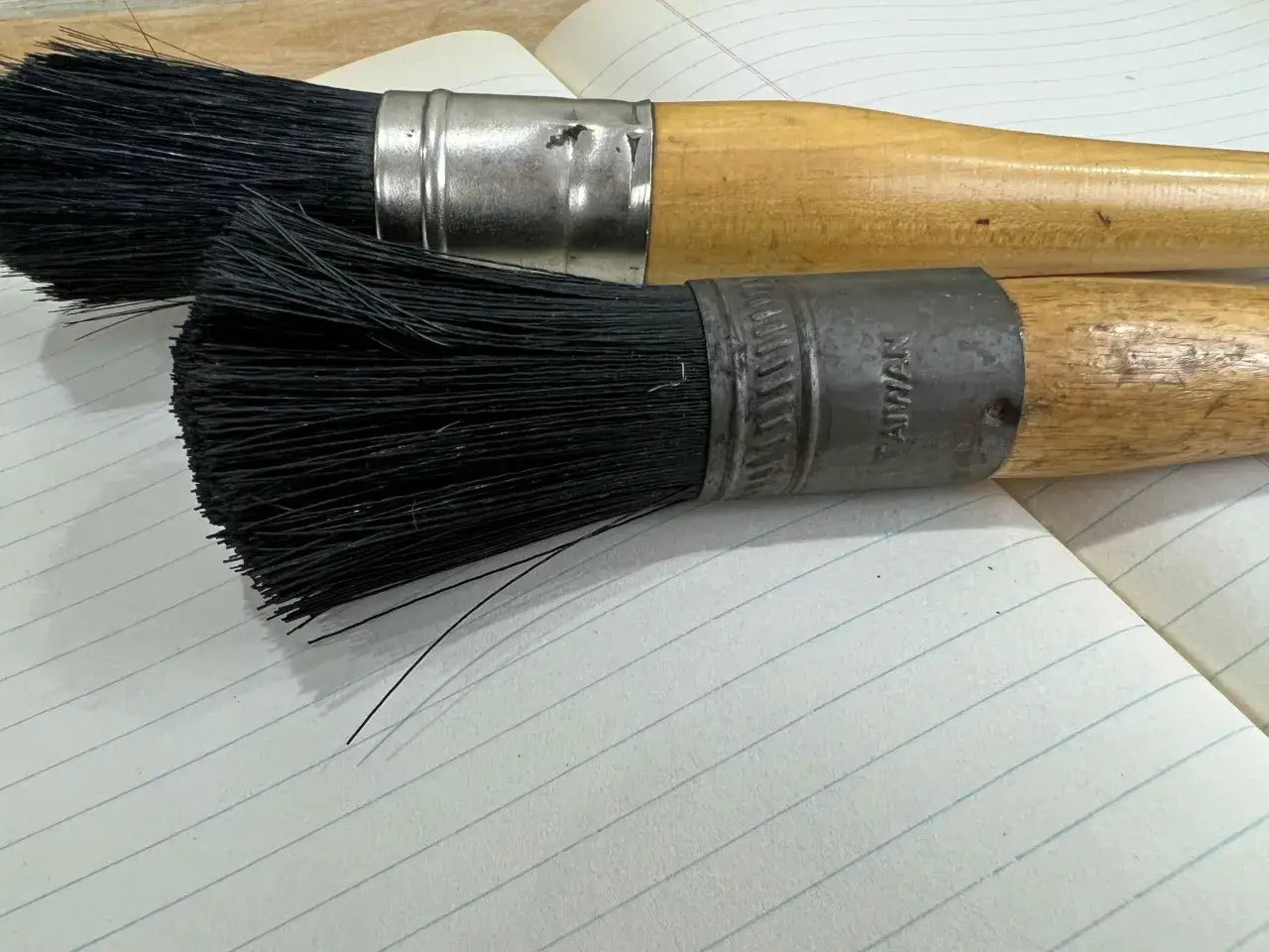 Deux pinceaux &agrave; manche en bois, pr&ecirc;ts pour nettoyer pinceau huile bois.