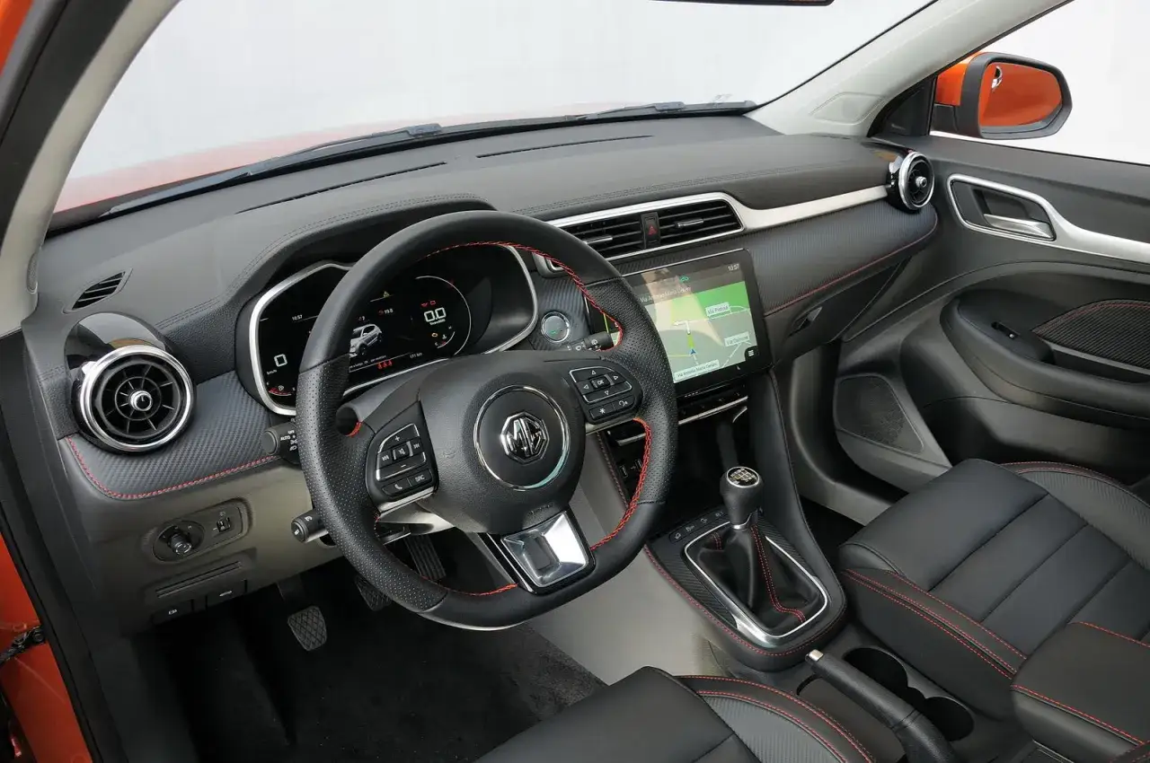 Interno di una MG ZS con volante sportivo, navigatore e cambio manuale. Nessun problema visibile, solo un'auto moderna.
