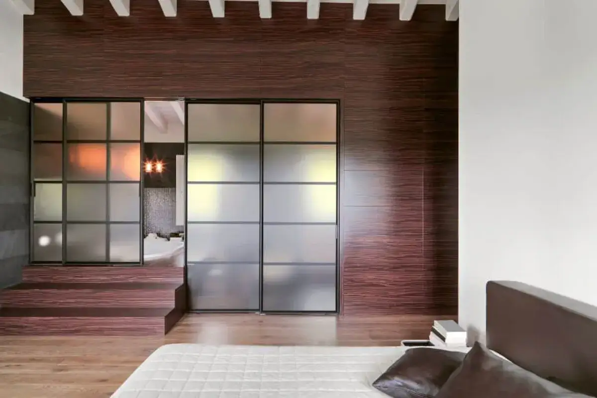 Puertas correderas de vidrio esmerilado y madera oscura muestran cómo separar ambientes, creando un espacio íntimo y moderno.