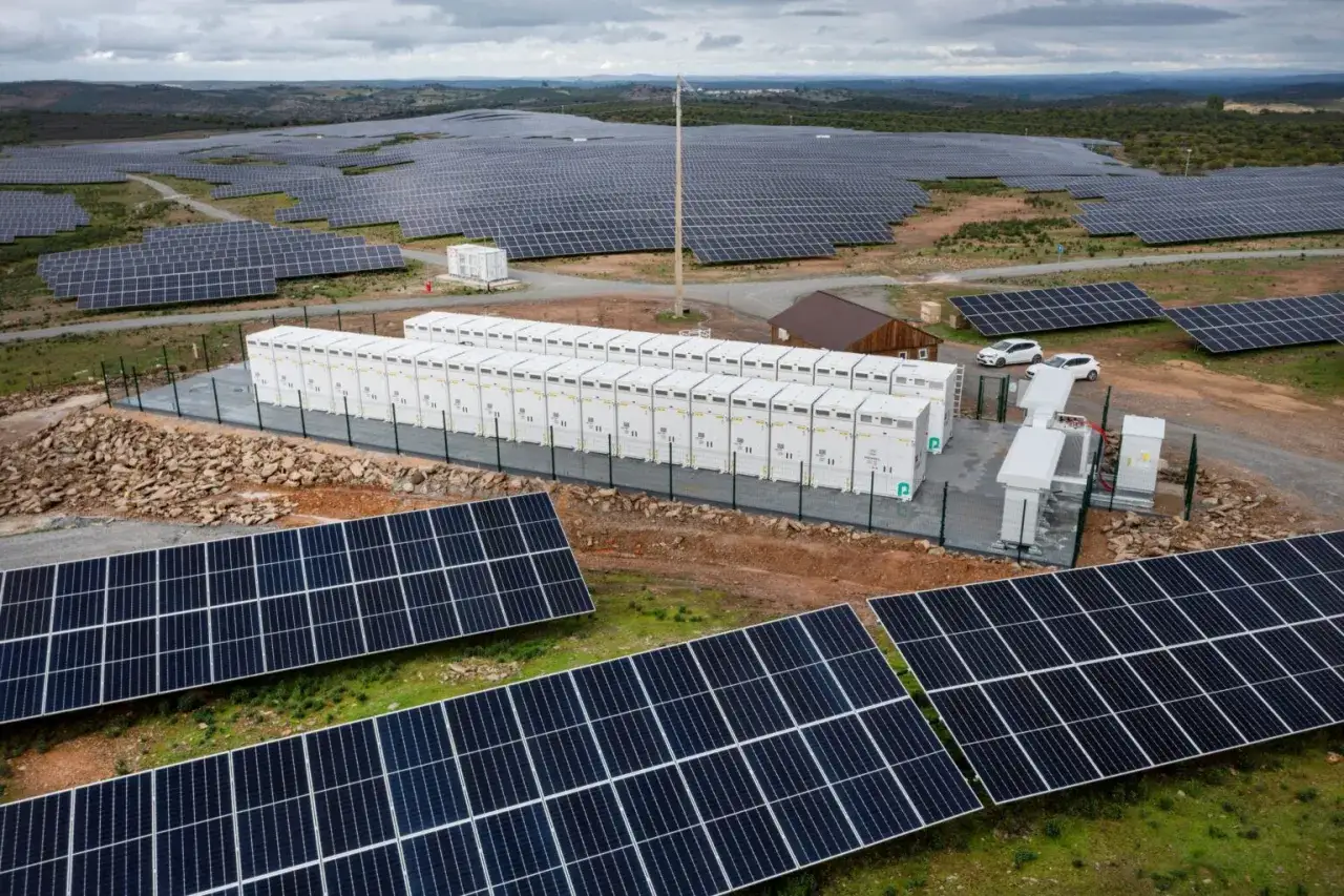 Große Solaranlage in Portugal mit vielen Reihen von Solarpanels und einer Batteriebank, die erneuerbare Energien speichert.