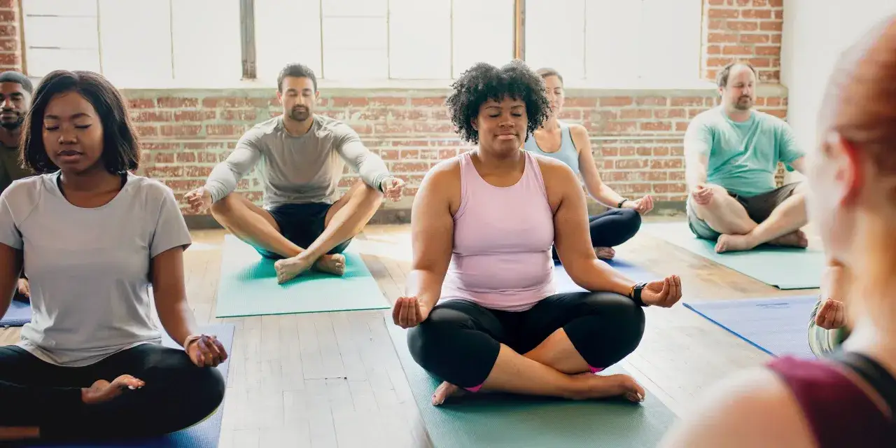 Grupo diverso meditando en postura de loto, buscando paz interior y fuerza con power vinyasa.