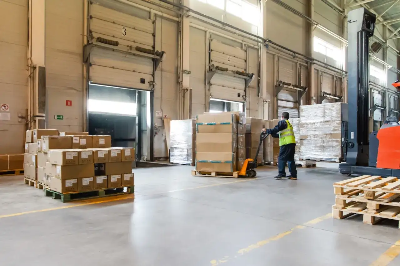 Trabajador mueve cajas en almac&eacute;n, cumpliendo la normativa de carga y descarga de camiones.