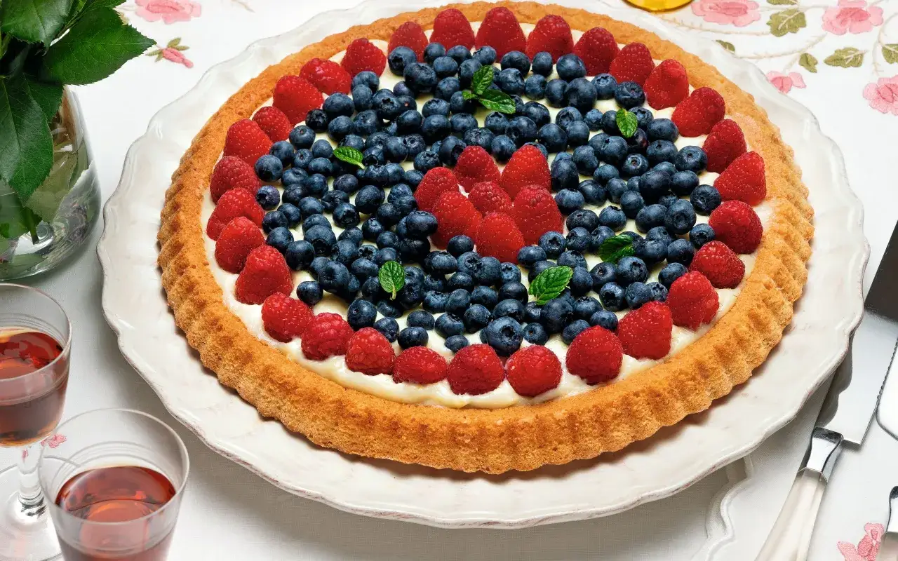 Torta con crema e frutti di bosco, un esempio di torte alla frutta particolari, con lamponi e mirtilli disposti a corona.