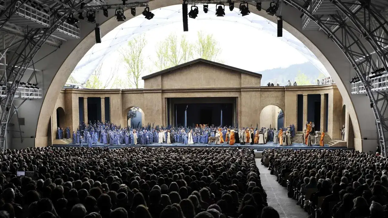 Gro&szlig;e B&uuml;hne mit vielen Darstellern in blauen Gew&auml;ndern bei den Passionsfestspielen Oberammergau. Tausende Zuschauer im Publikum.