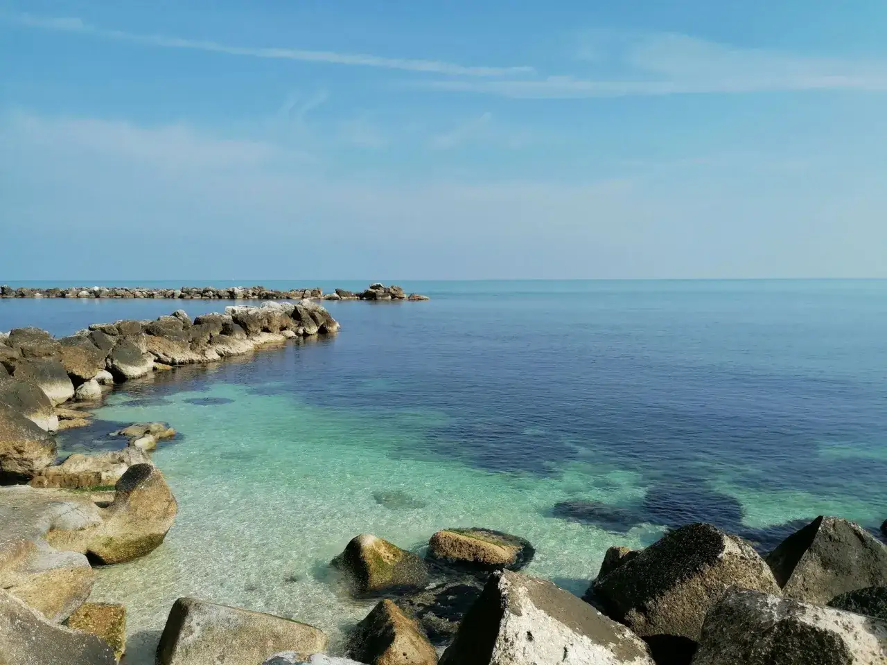 Kamienista plaża i turkusowa woda, idealne miejsce na spacer. Ankona co zobaczyć? To właśnie takie widoki!