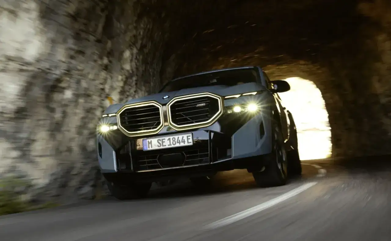 Nowy BMW XM wjeżdża z mrocznego tunelu, jego światła rozświetlają drogę.