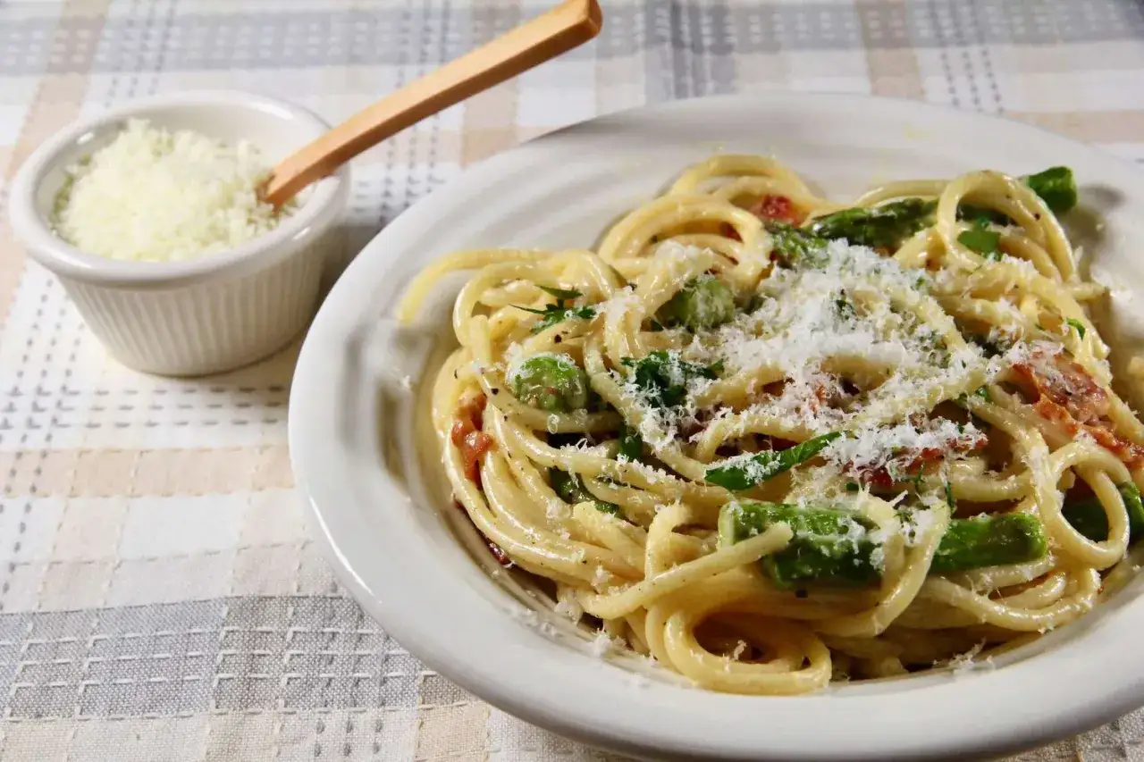 Spaghetti Carbonara mit grünem Spargel, garniert mit frisch geriebenem Parmesan. Ein köstliches Frühlingsgericht.