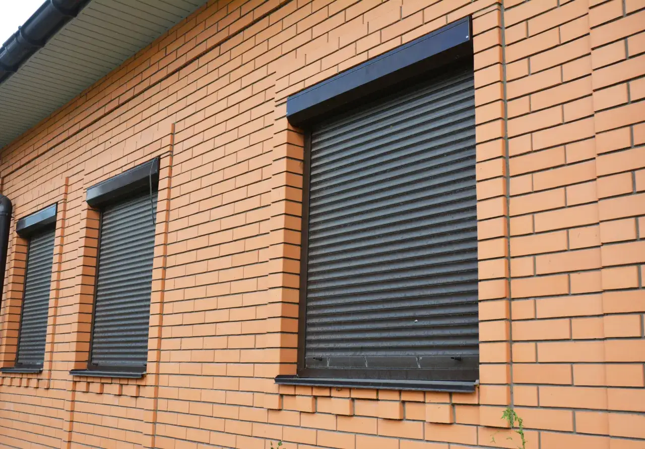 Prawda o rzekomym zakazie montażu rolet zewnętrznych w blokach pod opieką architekta. Okna z roletami na ceglanym budynku.
