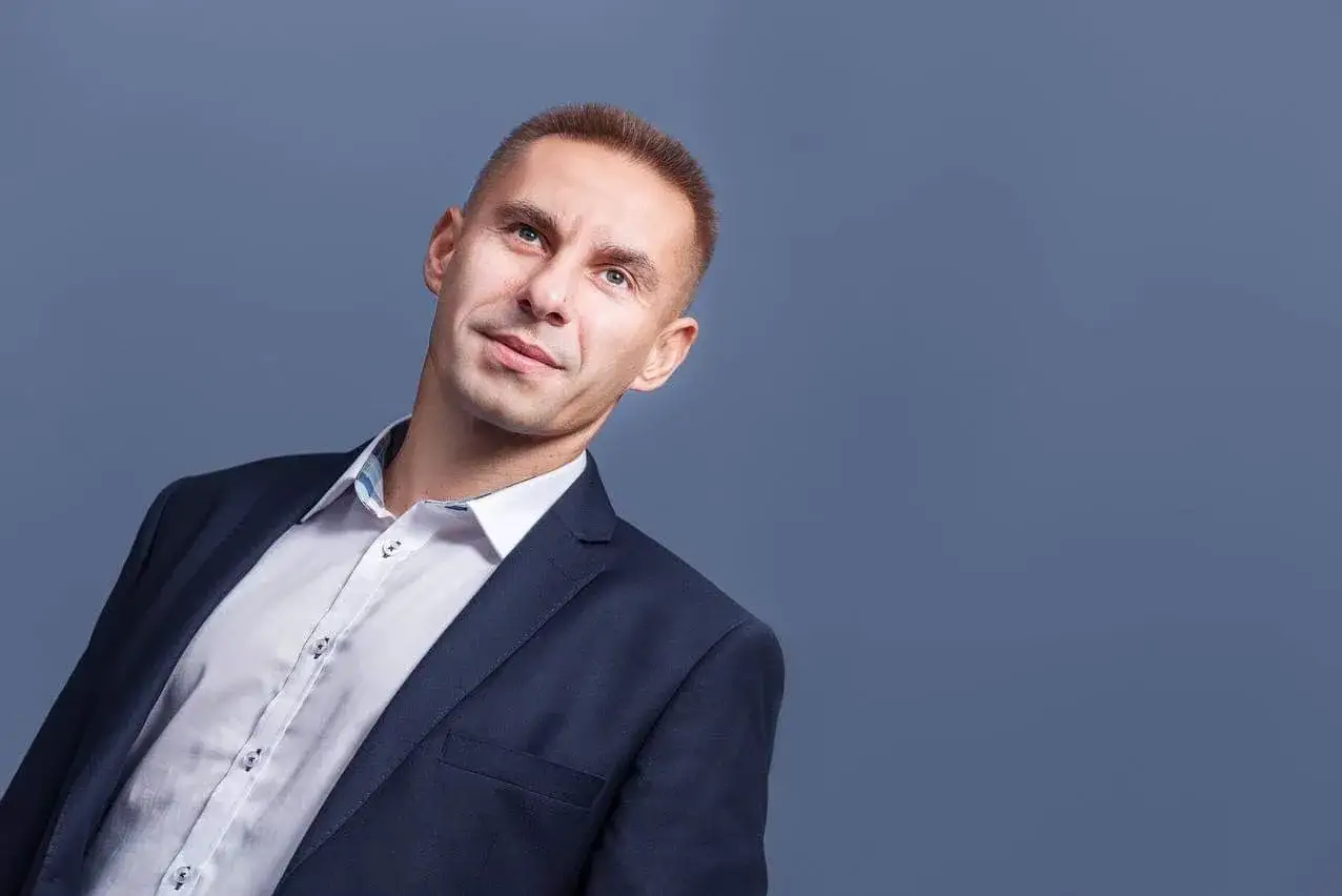 Mężczyzna w garniturze i białej koszuli, patrzący w górę.