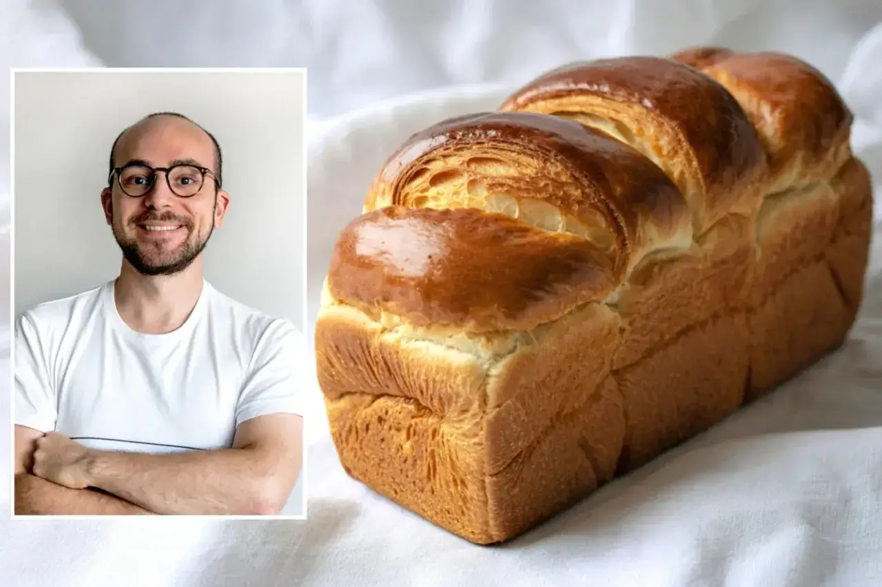 Mann mit Brille l&auml;chelt neben einem goldbraunen Brioche Brot. Ein tolles Brioche Brot Rezept!