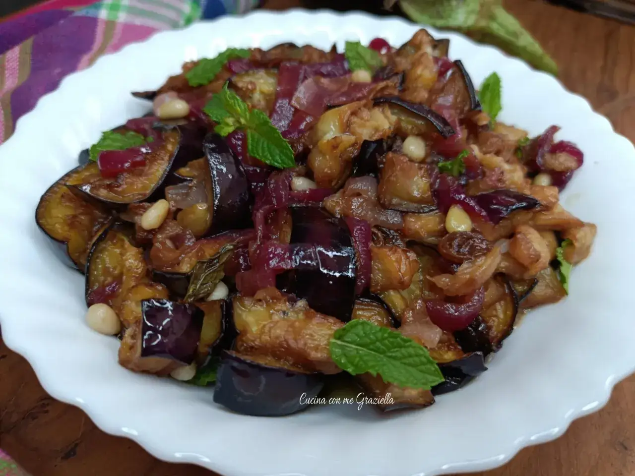 Melanzane in agrodolce, un sapore che ricorda la ricetta della nonna, con cipolle rosse, pinoli e menta fresca.