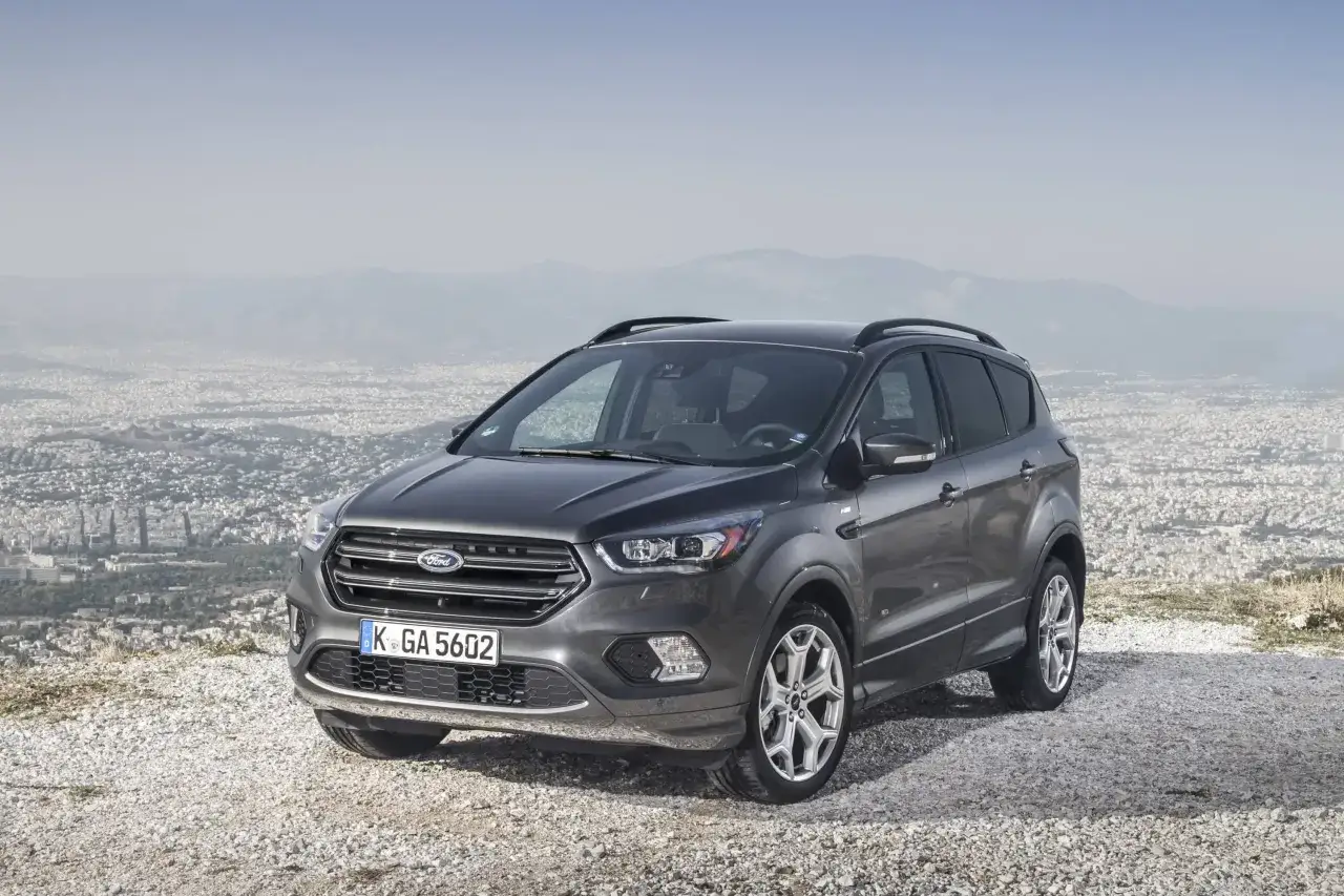 Un Ford Kuga gris, symbole de fiabilité, stationné sur un promontoire rocheux surplombant une ville.