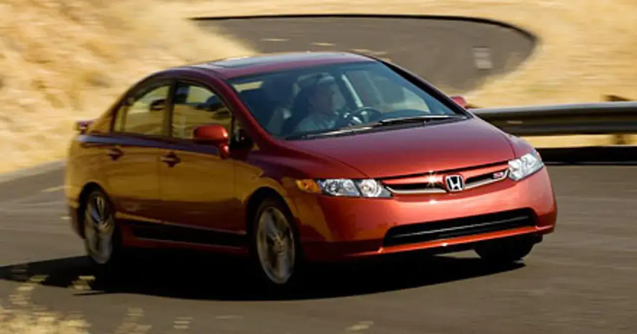 Czerwony Honda Civic Si zgrabnie pokonuje zakręt na pustynnej drodze.
