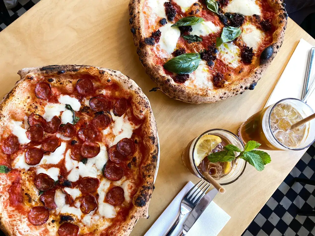 Dwie pyszne pizze, jedna z pepperoni, druga z pomidorami i mozzarellą, to dowód na najlepsza pizza warszawa. Do tego orzeźwiające napoje.