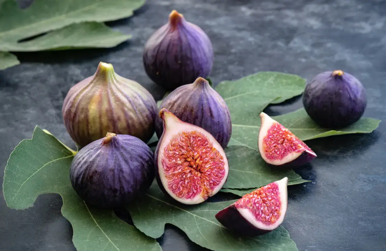Figues violettes mûres, coupées et entières, posées sur des feuilles vertes. Un délice issu du figuier arbre.