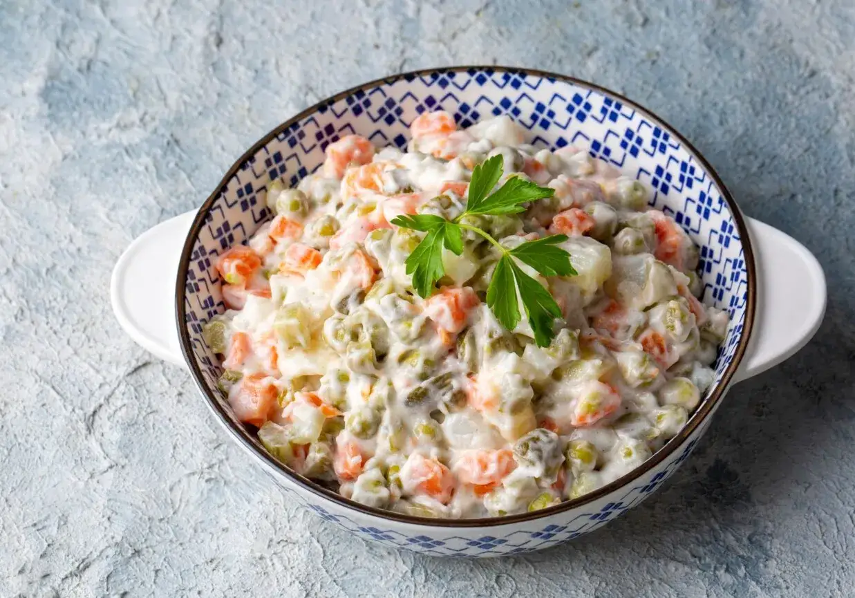 Sałatka jarzynowa w misce, z marchewką, groszkiem i ziemniakami. Zastanawiasz się, ile kcal ma sałatka jarzynowa?