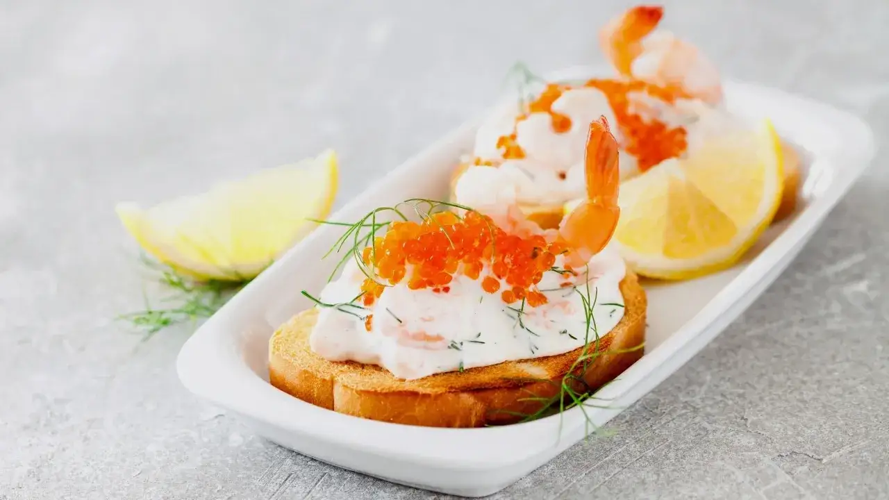 Toast Skagen med r&auml;kor, rom och dill. En klassiker p&aring; en vit bricka med citronklyftor.