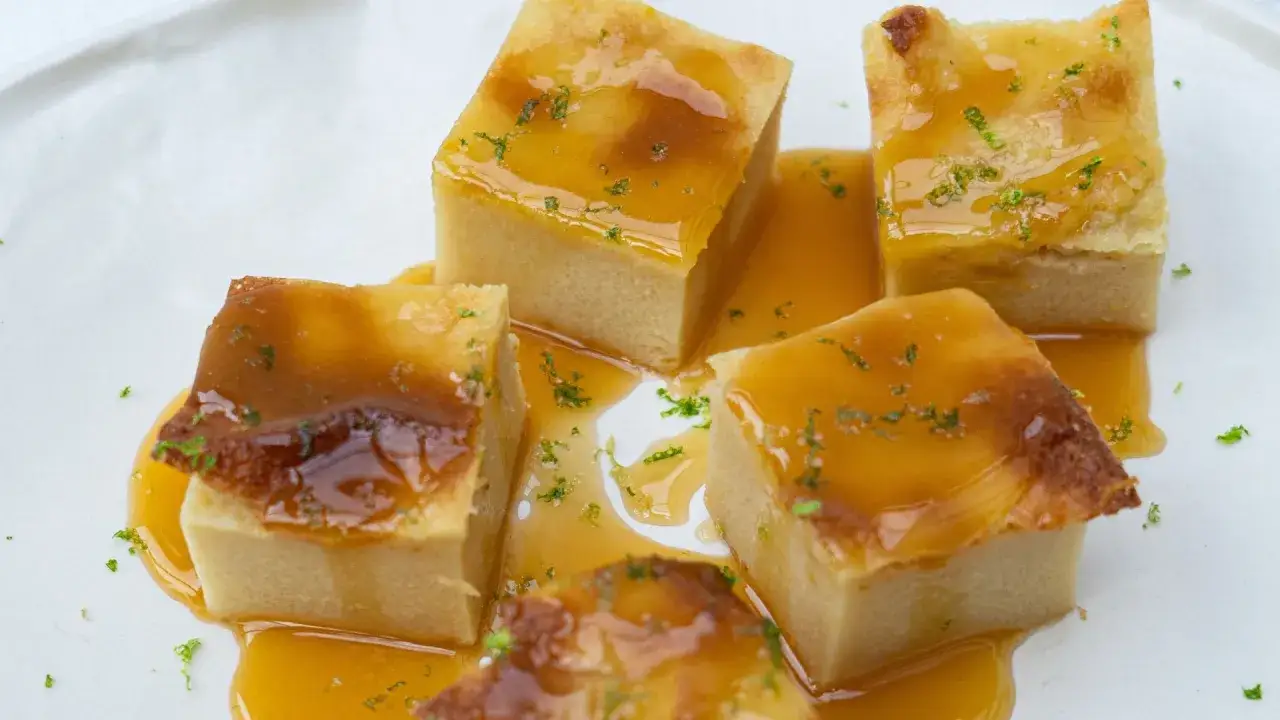 Délicieux gâteau de semoule en cubes, nappé d'un coulis doré et parsemé de zestes verts. Un délice visuel et gustatif.