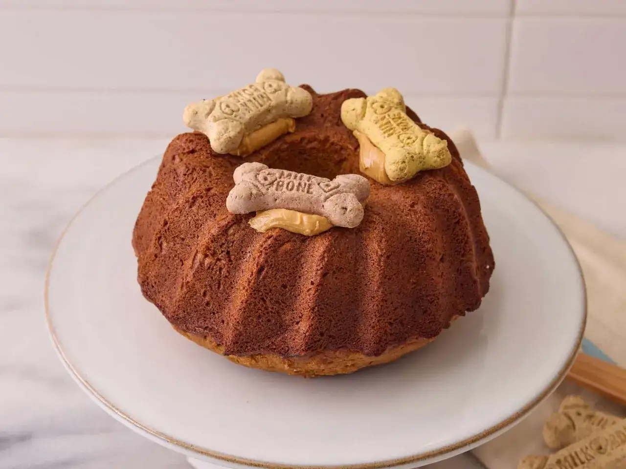 Un délicieux gâteau pour chien, orné de biscuits en forme d'os et de touches de beurre de cacahuète. Un régal parfait pour votre compagnon à quatre pattes !
