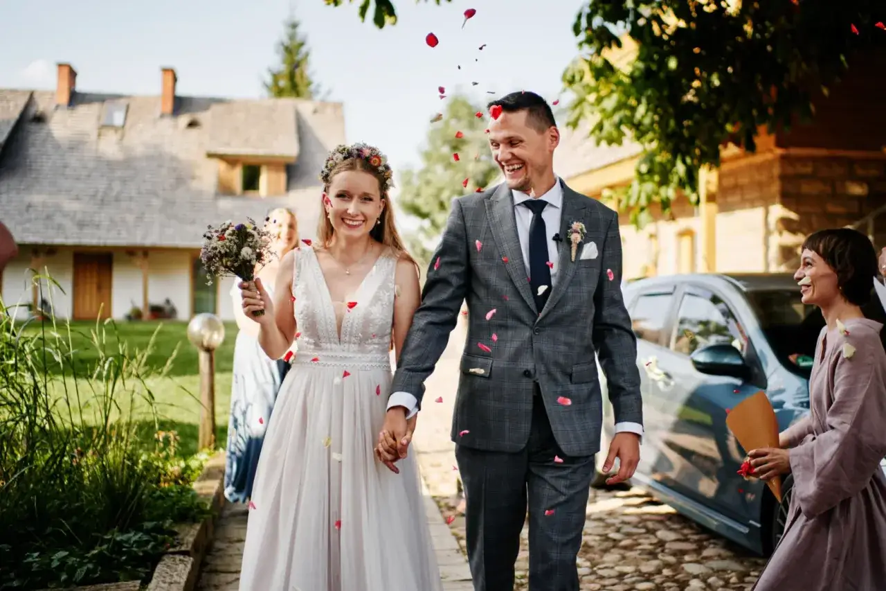 Szczęśliwa para młoda idzie w deszczu płatków róż. Wspaniałe rady dla nowożeńców na początku wspólnej drogi.