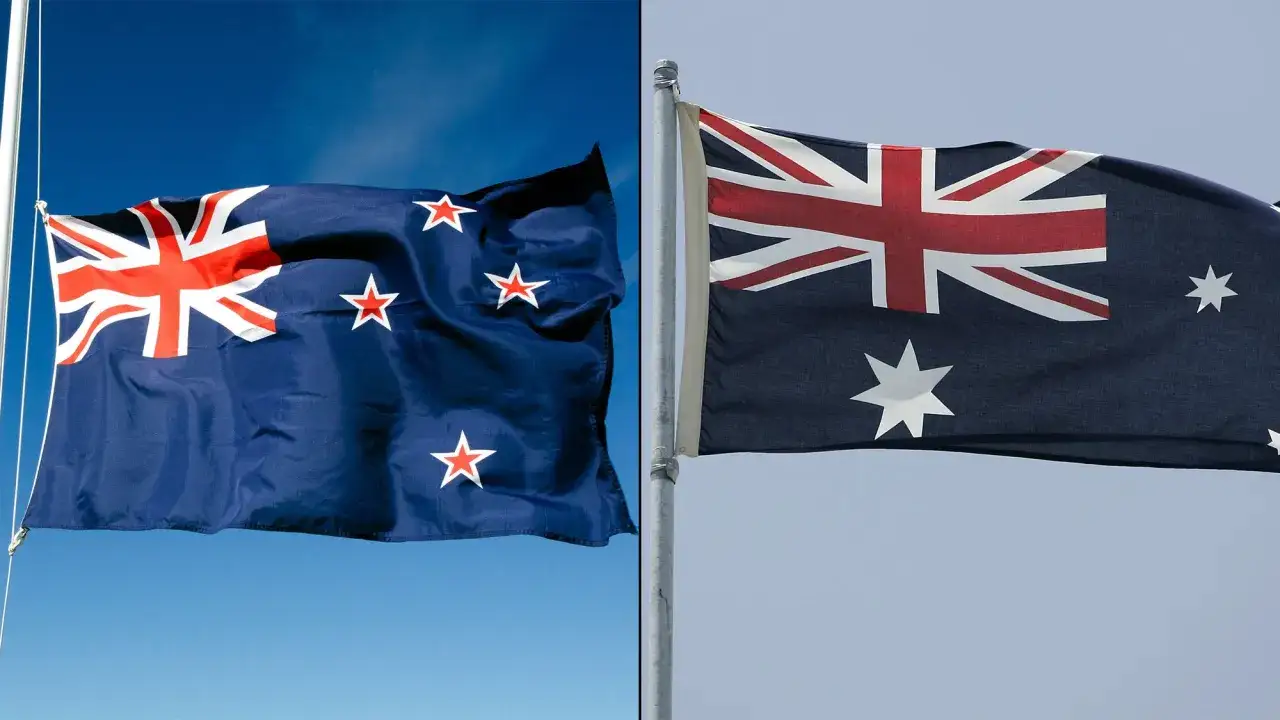Flaga Australii i Nowej Zelandii powiewają na wietrze. Obie flagi mają brytyjską flagę w lewym górnym rogu, ale różnią się gwiazdami.
