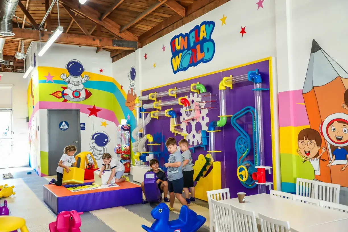 Children enjoy an indoor activity for toddlers at Fun Play World, with colorful murals and interactive ball tubes.