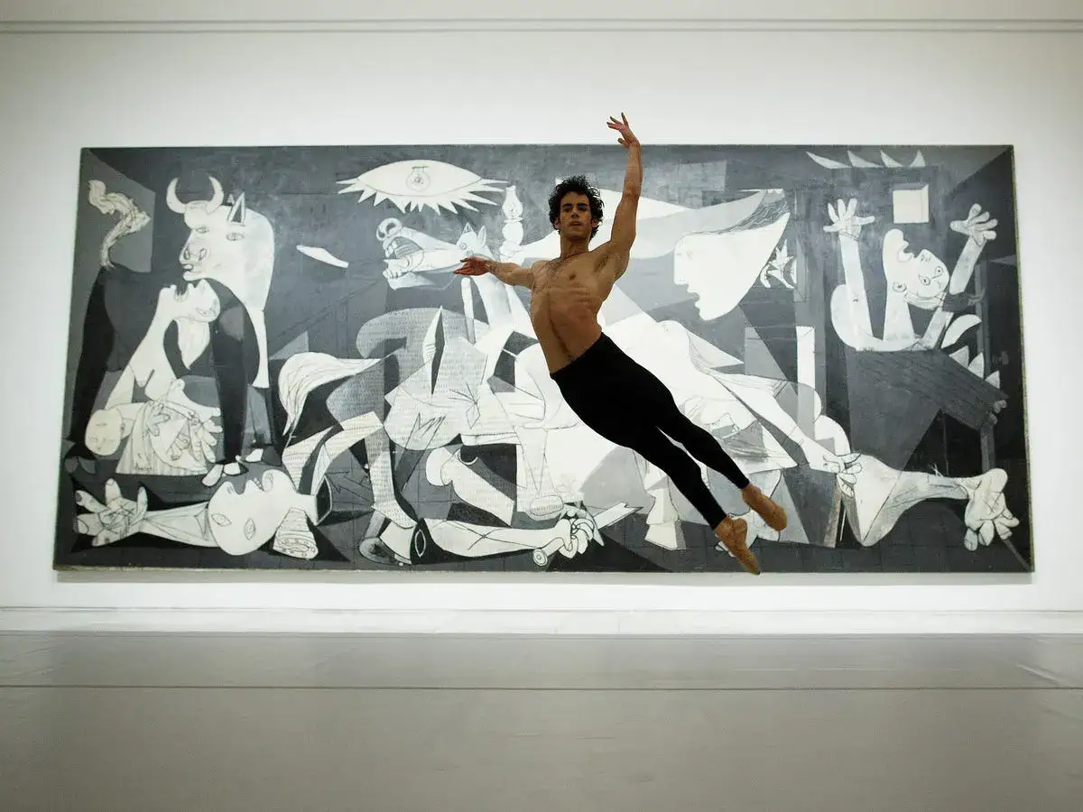 Un ballerino in volo davanti a Guernica, capolavoro dell'artista spagnolo famoso Picasso.