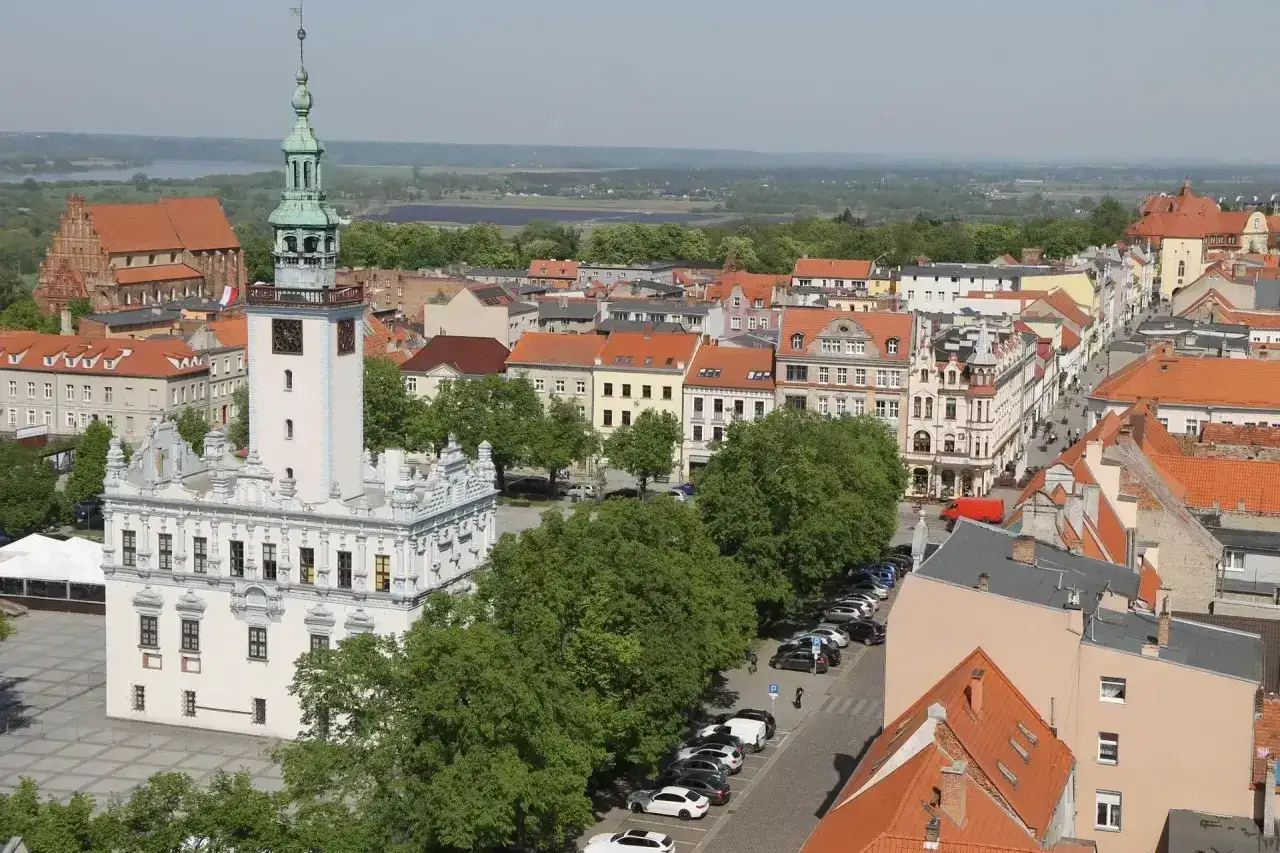 Widok na rynek w Chełmnie z ratuszem i wieżą. W tle kamienice i zieleń, malownicze chełmno atrakcje.