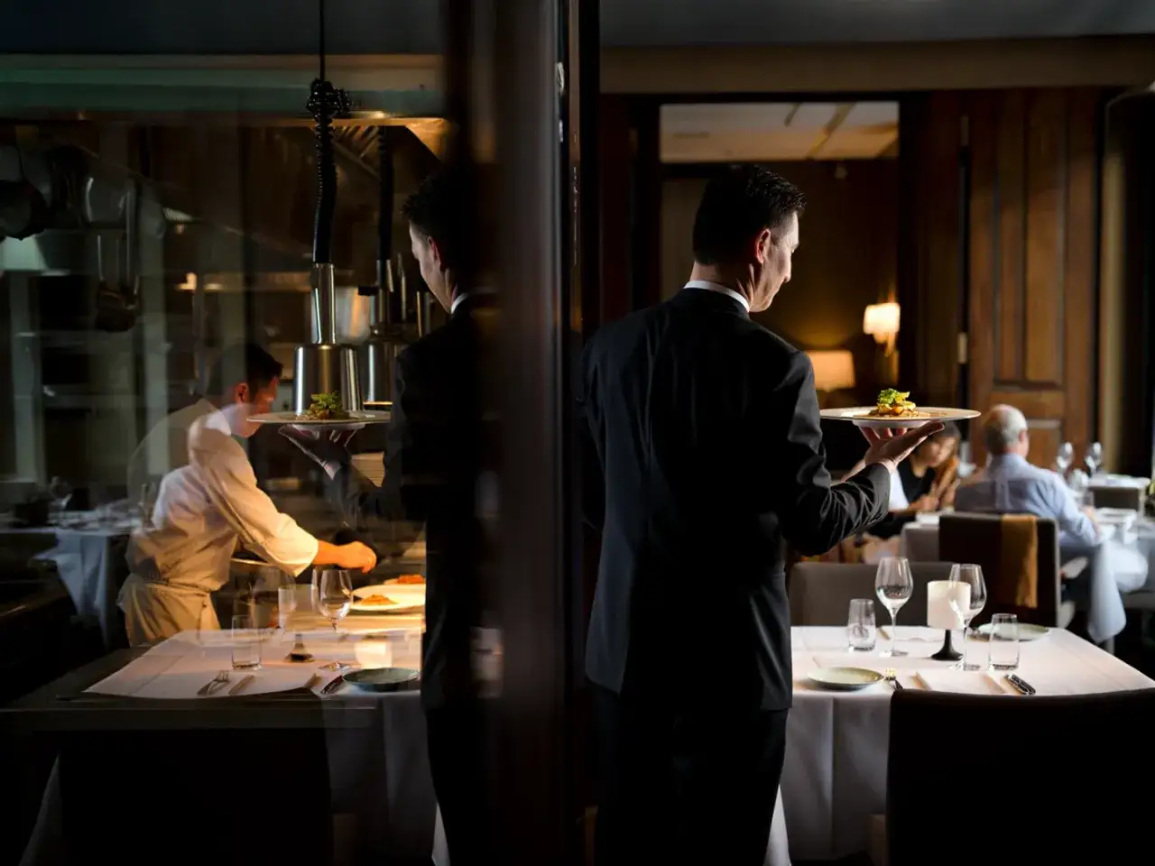 Camarero elegante sirviendo un plato, reflejando las cualidades de un camarero: profesionalismo y atenci&oacute;n al detalle.