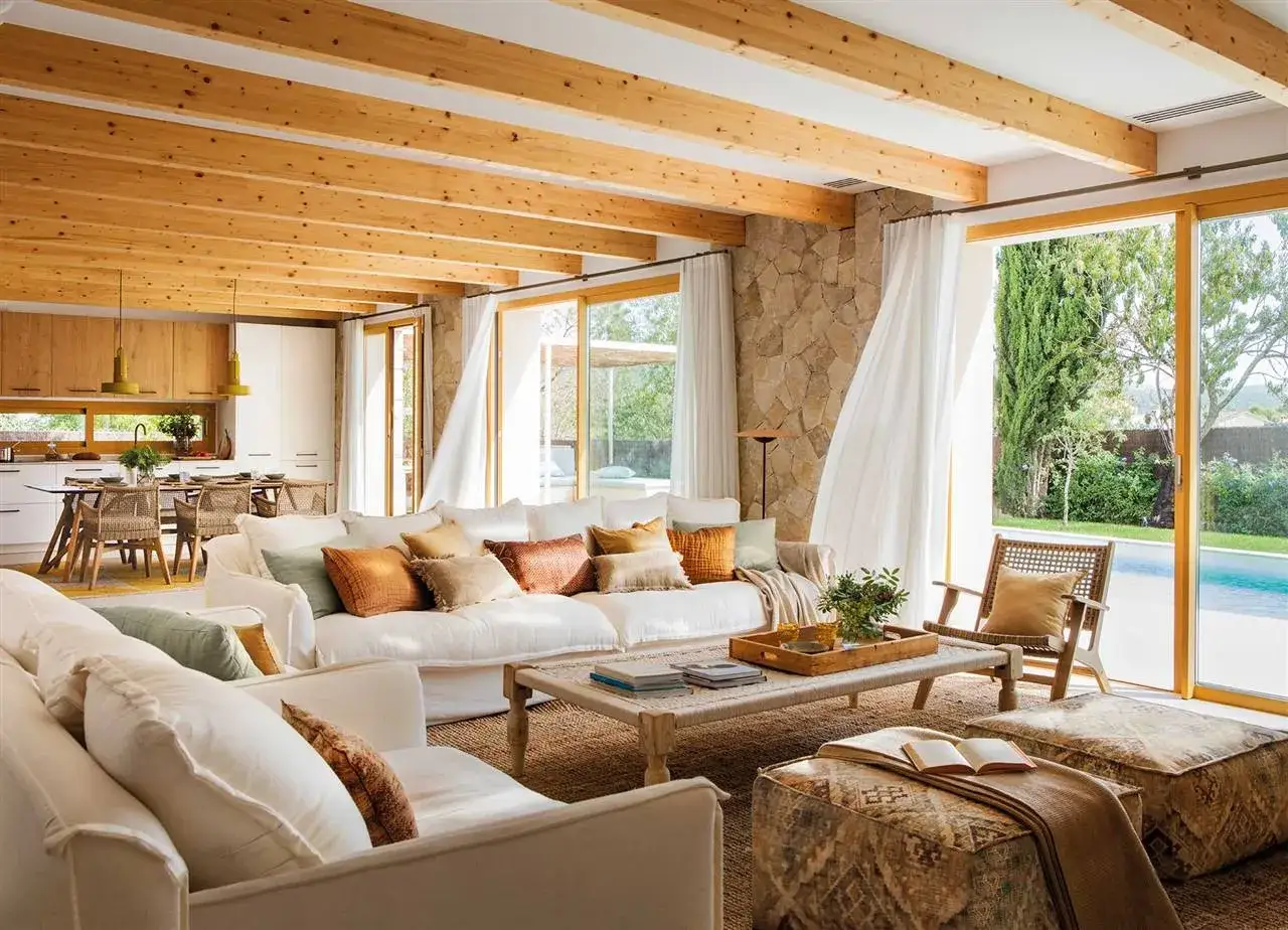 Salones colores neutros con sof&aacute;s blancos, vigas de madera y vistas a piscina.