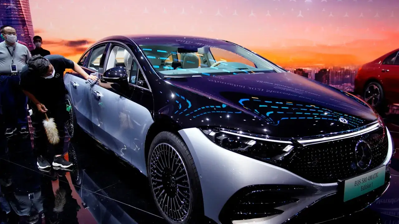 Opiekun dopieszcza błyszczący lakier luksusowego **Mercedes EQS**, przygotowując go na pokaz.