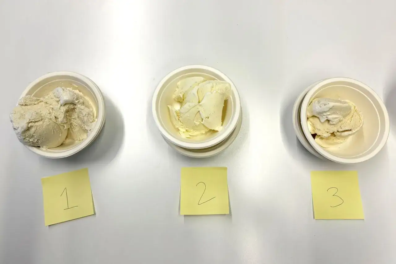 Drei Schalen mit cremigem, gelbem Eis stehen nebeneinander, jede mit einer nummerierten Notiz.
