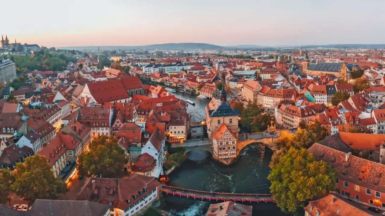 Blick über die malerische Bamberger Innenstadt mit ihren roten Dächern und dem Fluss Regnitz. Das Alte Rathaus ragt stolz aus dem Wasser.