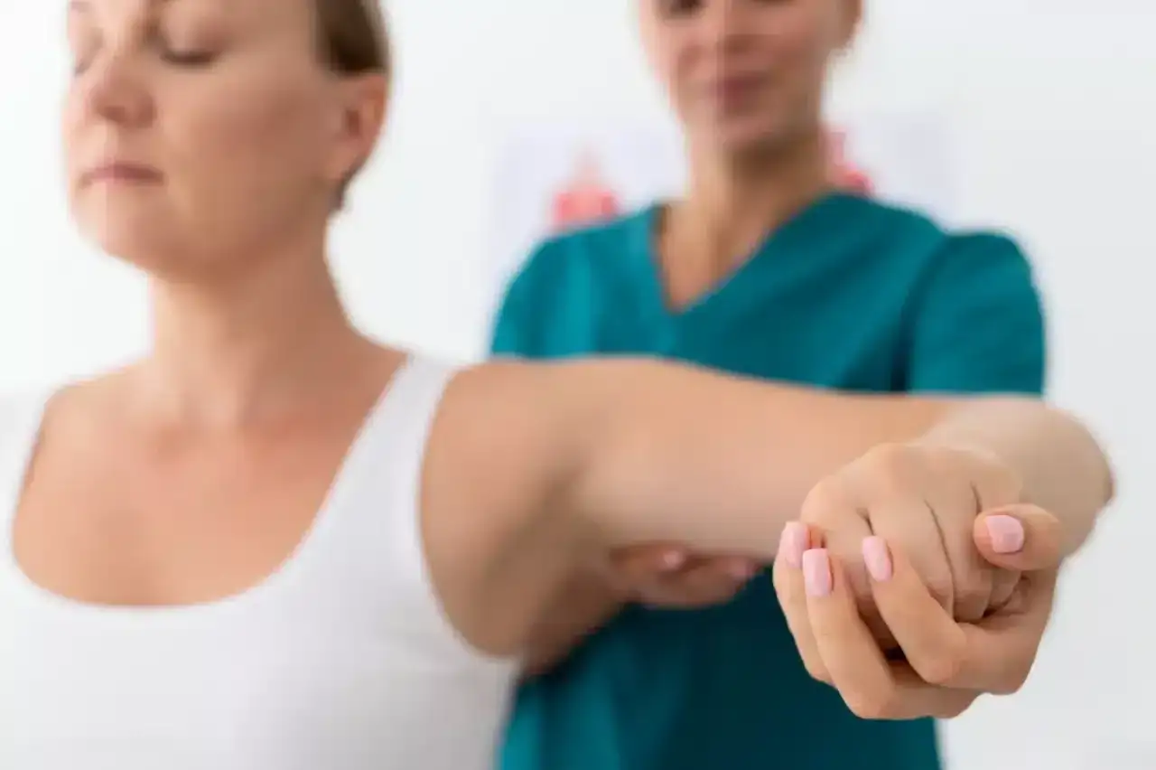 Fizjoterapeuta pomaga pacjentce z zespołem skrzyżowania dolnego w ćwiczeniach ramienia.