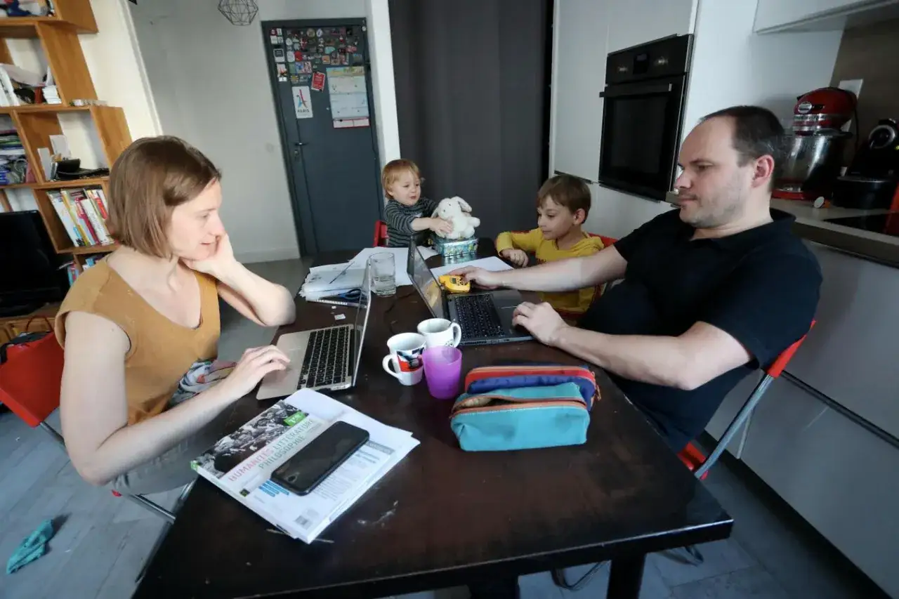 Familie am Esstisch, Eltern arbeiten an Laptops, Kinder spielen. Ein Beispiel für die Balance zwischen work and life.