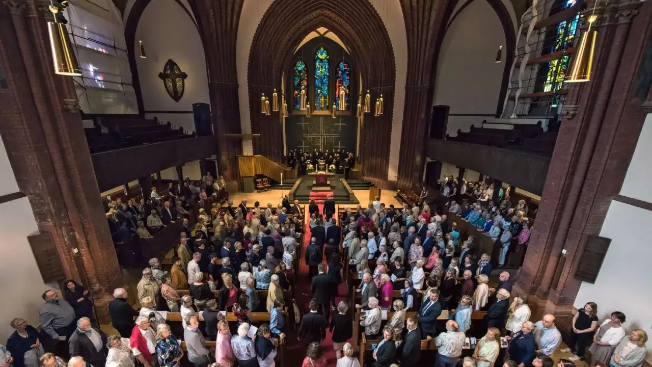 Menschen versammeln sich in einer Kirche, um zu erfahren, was bedeutet evangelisch. Ein Chor singt, während die Gemeinde zuhört.