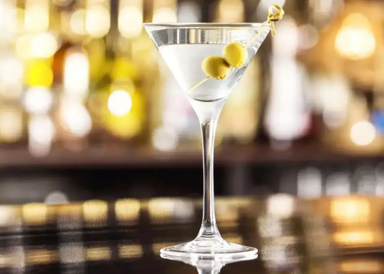 Klasyczny martini dry przepis: schłodzony gin, odrobina wermutu i dwie oliwki. Idealny drink na wieczór.