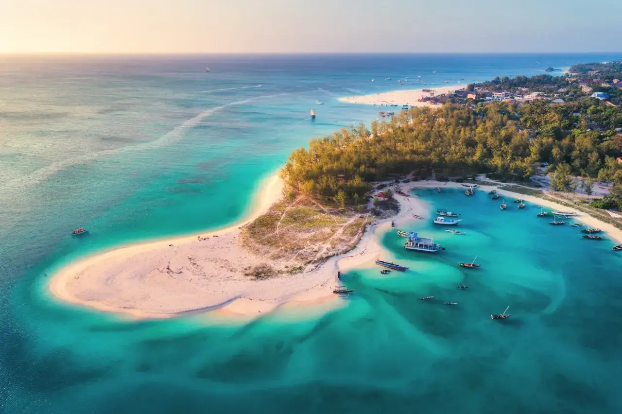 Piękna plaża na Zanzibarze z turkusową wodą i łodziami. Zastanawiasz się, ile czasu leci się na Zanzibar?