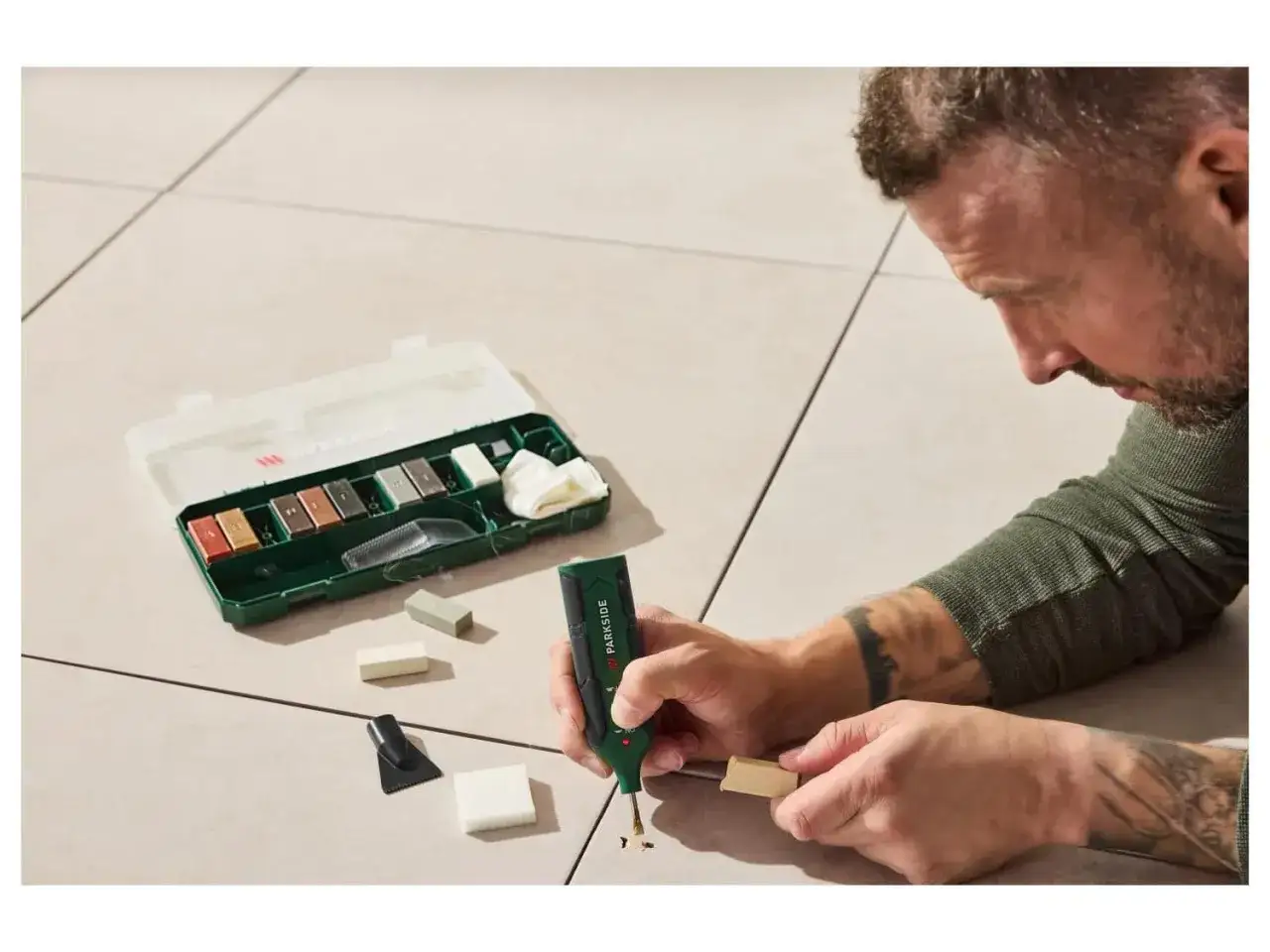 Un homme r&eacute;pare un carrelage ray&eacute; avec un kit de r&eacute;paration.