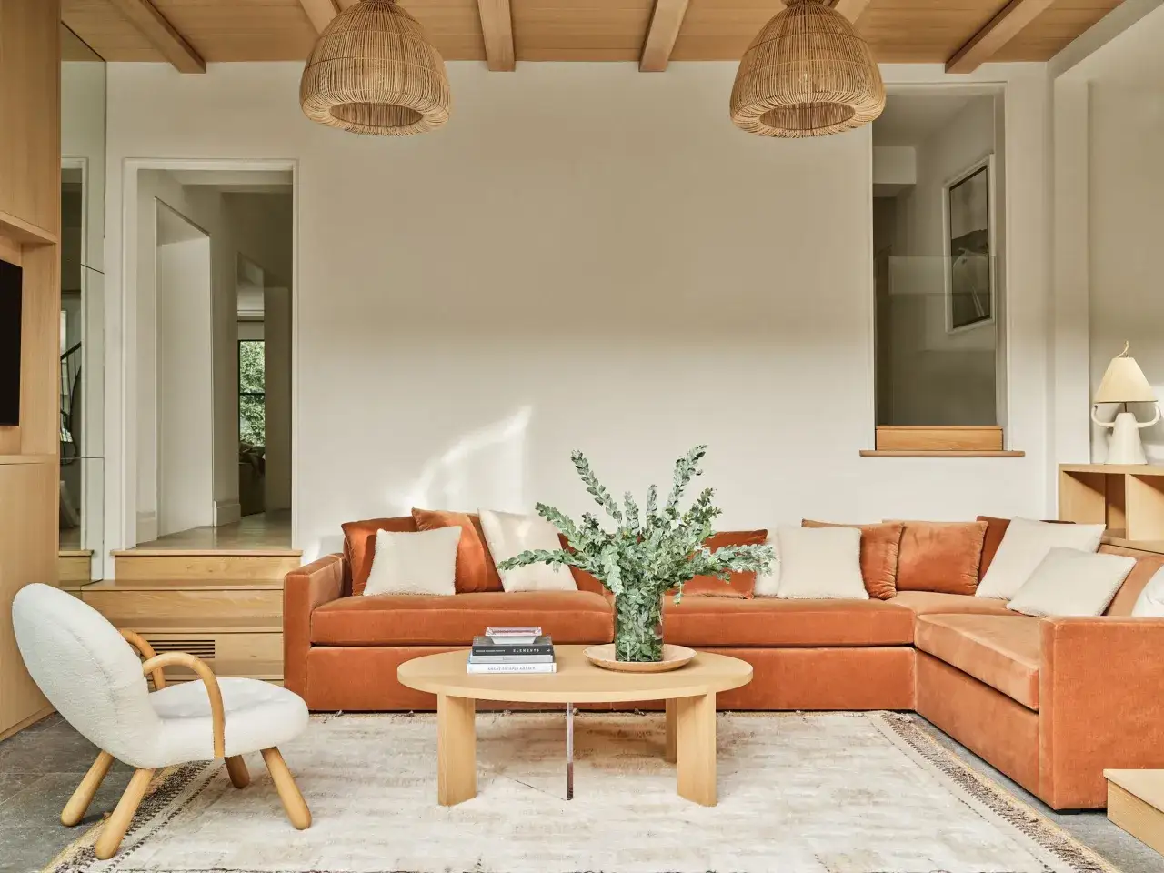 Gemütliches Wohnzimmer mit orangefarbenem Sofa, beigem Teppich und Holzmöbeln, das die feng shui regeln für Harmonie und Fluss widerspiegelt.