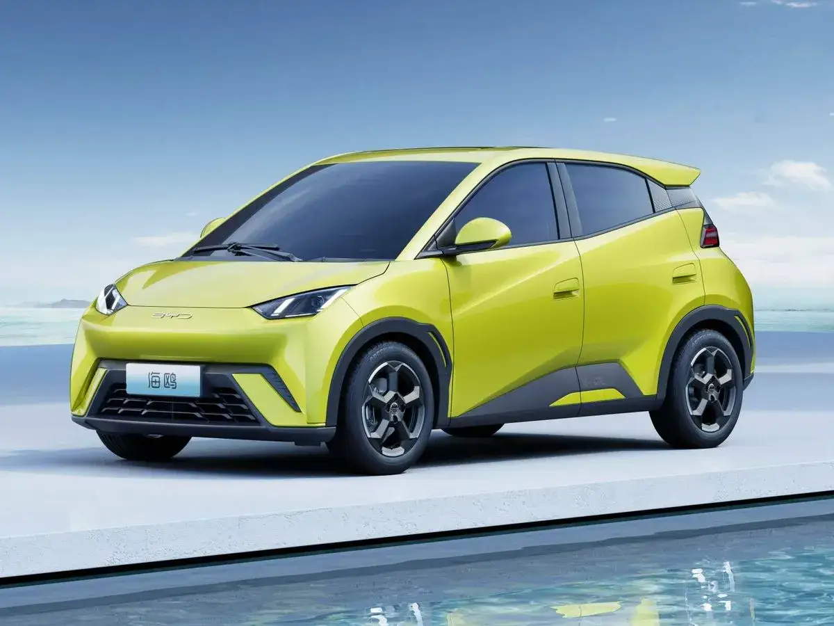 Un ágil coche urbano de color amarillo brillante, perfecto para la ciudad, descansa junto a un reflejo de agua bajo un cielo azul.