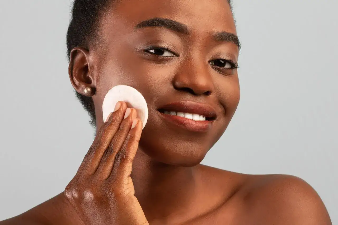 Mujer sonriente se aplica t&oacute;nico con un disco de algod&oacute;n, un paso clave para saber cada cuanto exfoliar la cara y mantenerla radiante.