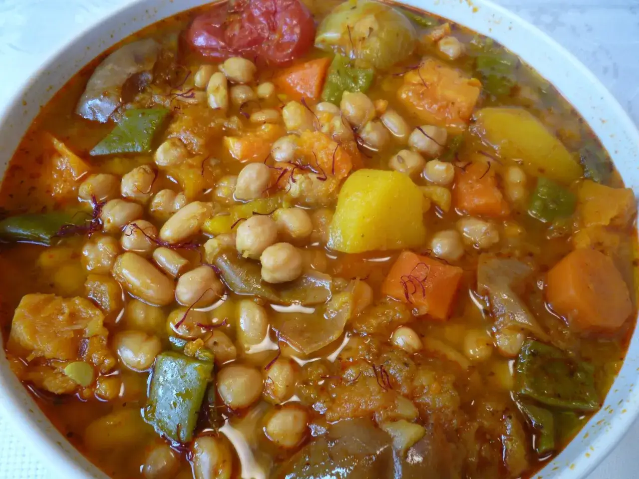 Un plato humeante de olla gitana murciana, rebosante de garbanzos, patatas, zanahorias, pimientos y tomate, con hebras de azafr&aacute;n.