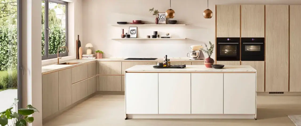 Elegantes dise&ntilde;os cocinas con gabinetes de madera clara, encimeras de m&aacute;rmol y electrodom&eacute;sticos integrados. Una isla central blanca y una ventana con vista al jard&iacute;n.