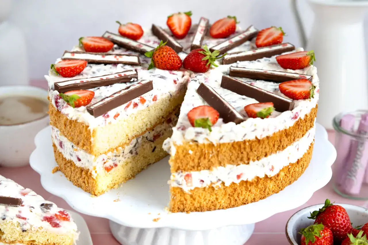 Saftige Joghurette Torte mit Erdbeeren und Schokost&uuml;ckchen, dekoriert mit frischen Erdbeeren und Schokoriegeln.