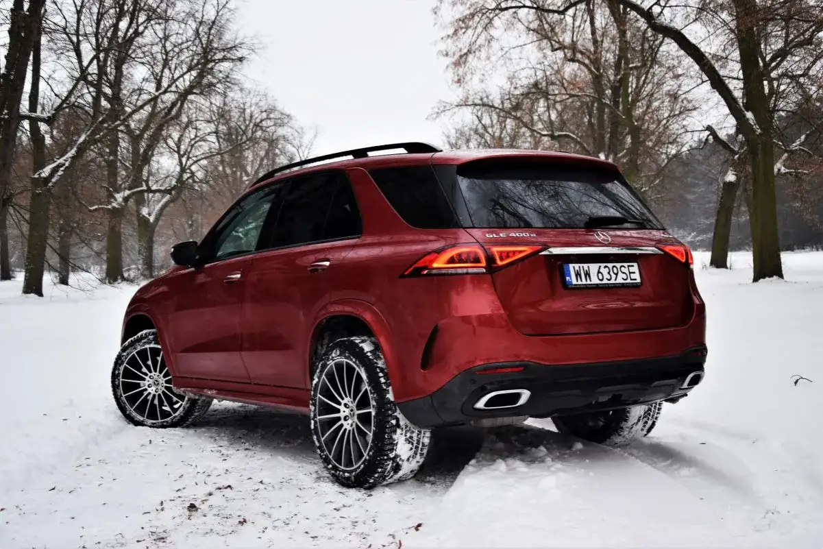 Czerwony Mercedes GLE 400d na zimowych oponach w śnieżnym lesie.