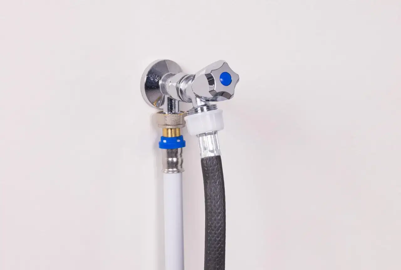 Robinet machine &agrave; laver chrom&eacute; avec deux tuyaux connect&eacute;s, un blanc et un noir tress&eacute;, pr&ecirc;t pour le cycle de lavage.