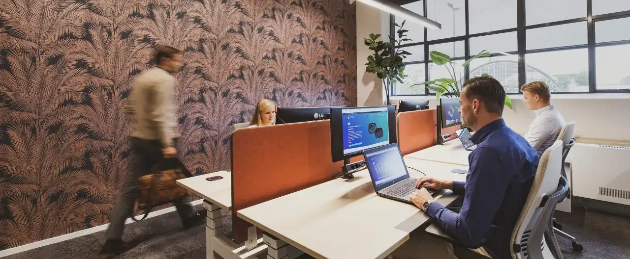 Ufficio moderno con persone al lavoro. Un uomo con borsa cammina, una donna lavora al computer, un altro uomo &egrave; seduto alla scrivania. Un'ottima ambientazione per il **setter lavoro**.