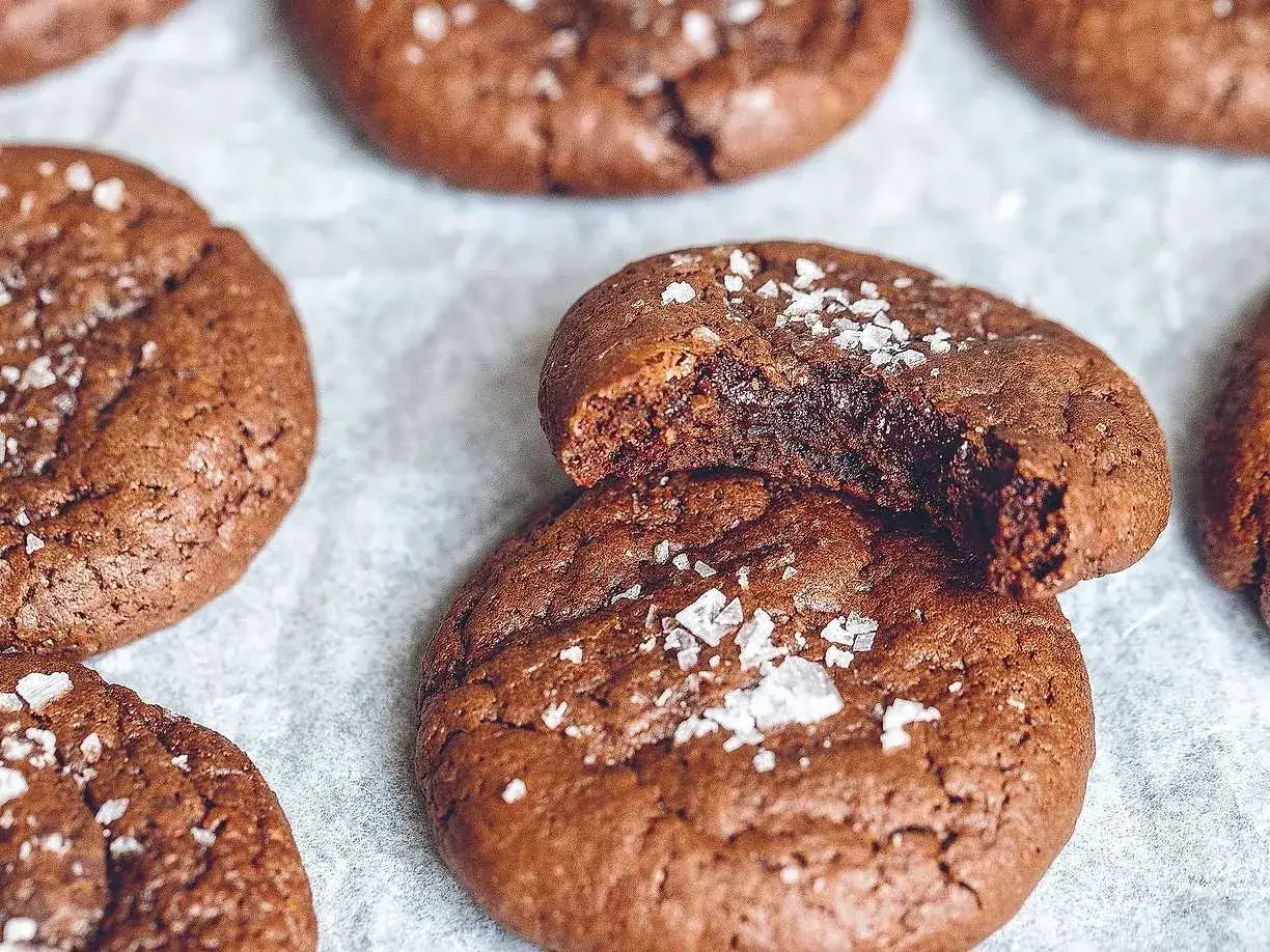 Mumsiga kladdkake cookies med flingsalt. En är uppäten och avslöjar en härligt kladdig insida.